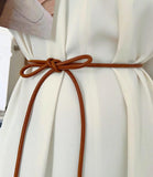 Women's thin rope belt in cognac vegan leather tied over a white dress