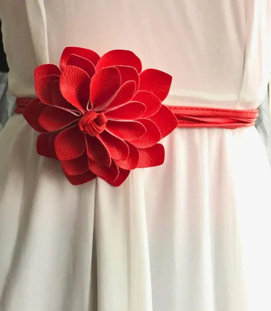 Women's red flower belt with long tie ends styled on a white dress