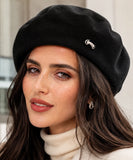 Woman wearing a black wool-blend French beret with a metal brooch