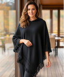 Women's hooded poncho sweater in black chunky knit with fringe trim, front view