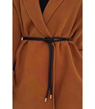 Women's thin rope belt in black vegan leather tied over a rust wrap coat