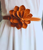 Women's burnt orange flower belt with long tie ends on a white dress