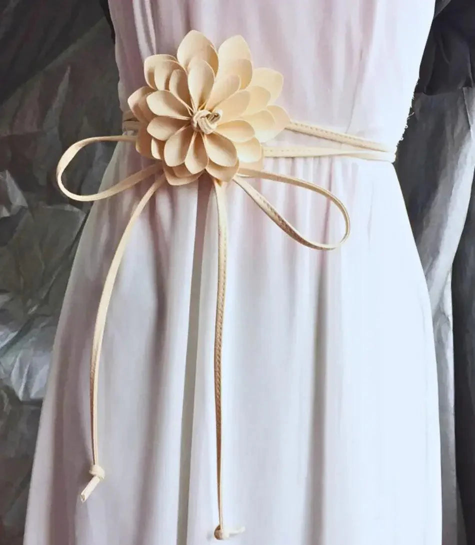 Women's ivory flower belt with long tie ends styled on a white dress