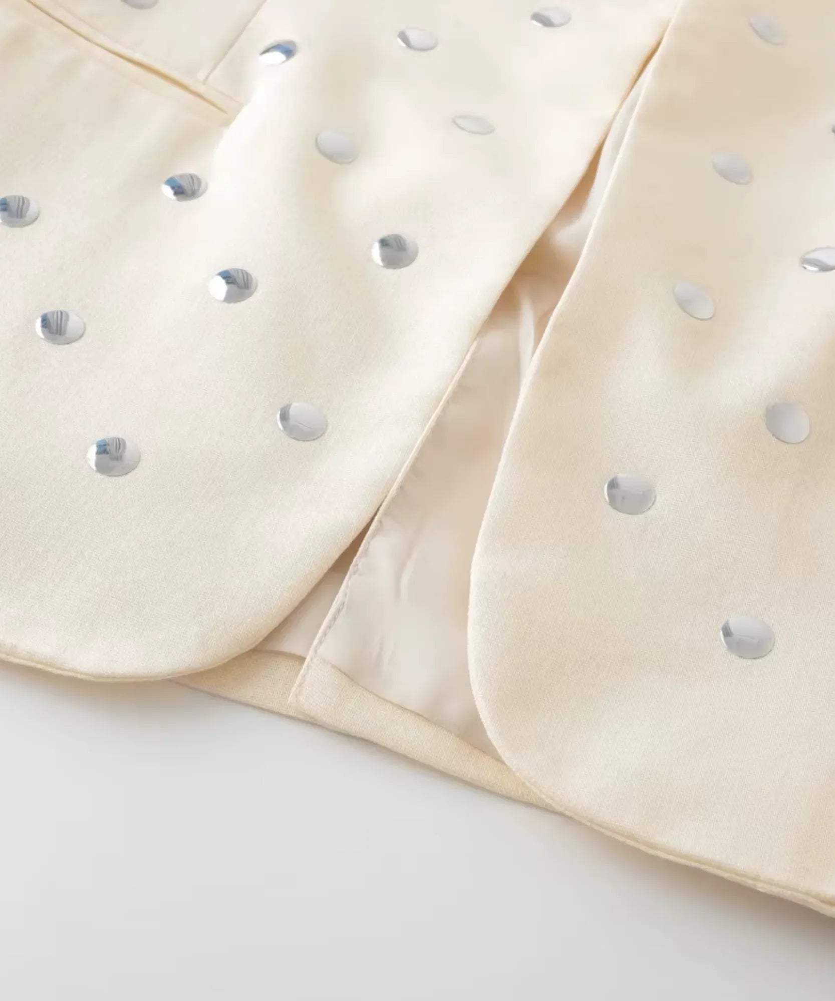 Close up of the silver studs on the collar of the beige blazer