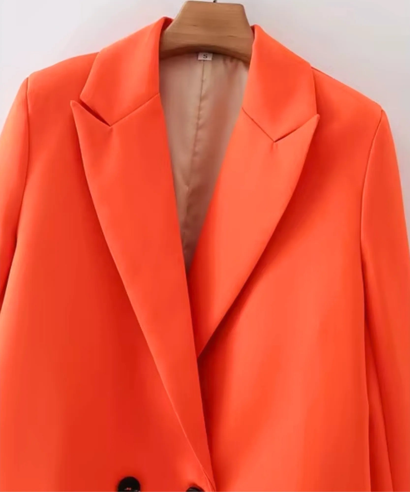 Close up of the lapel and lining on an orange double breasted blazer