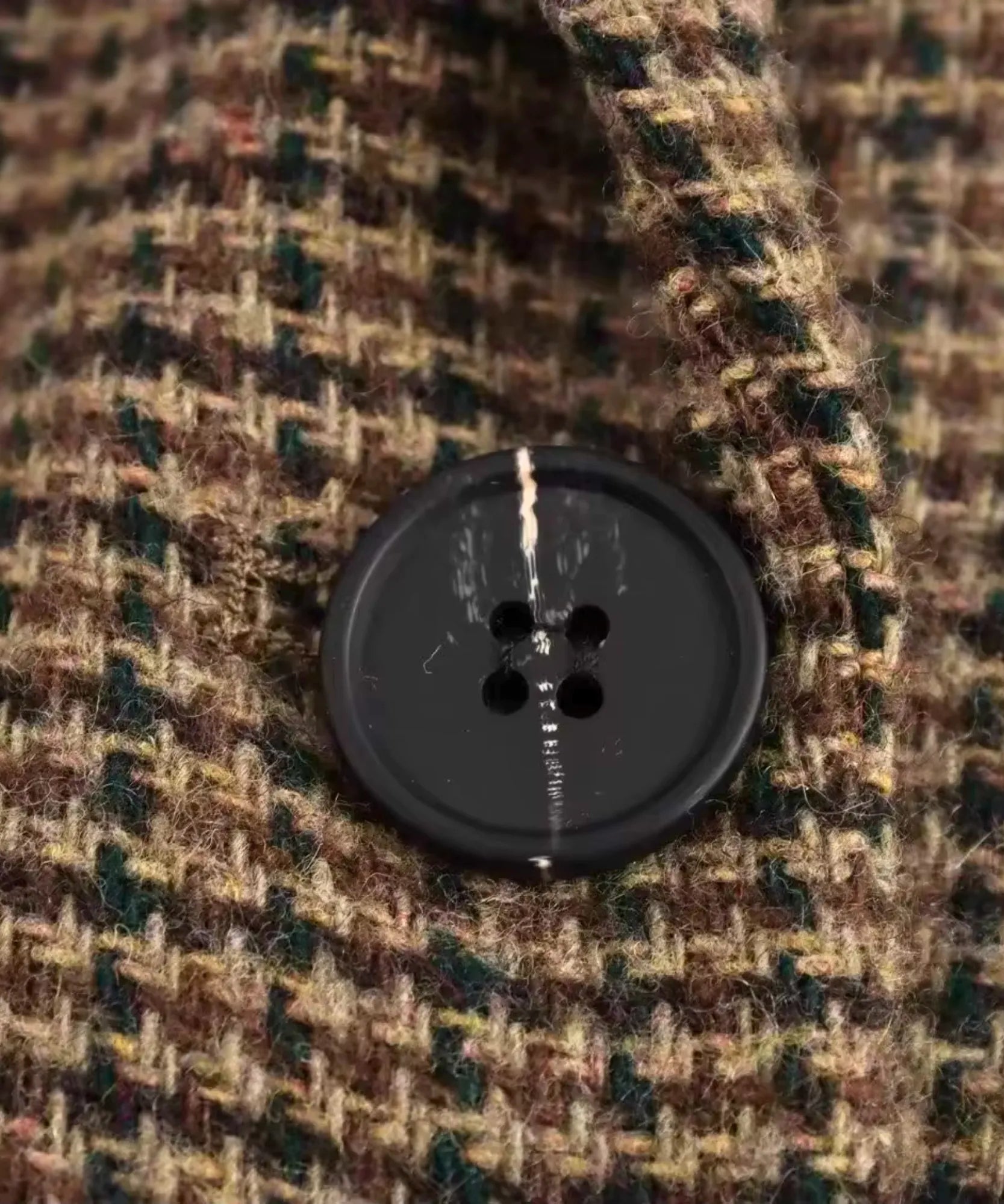 Close up of the black button on the brown houndstooth tweed blazer