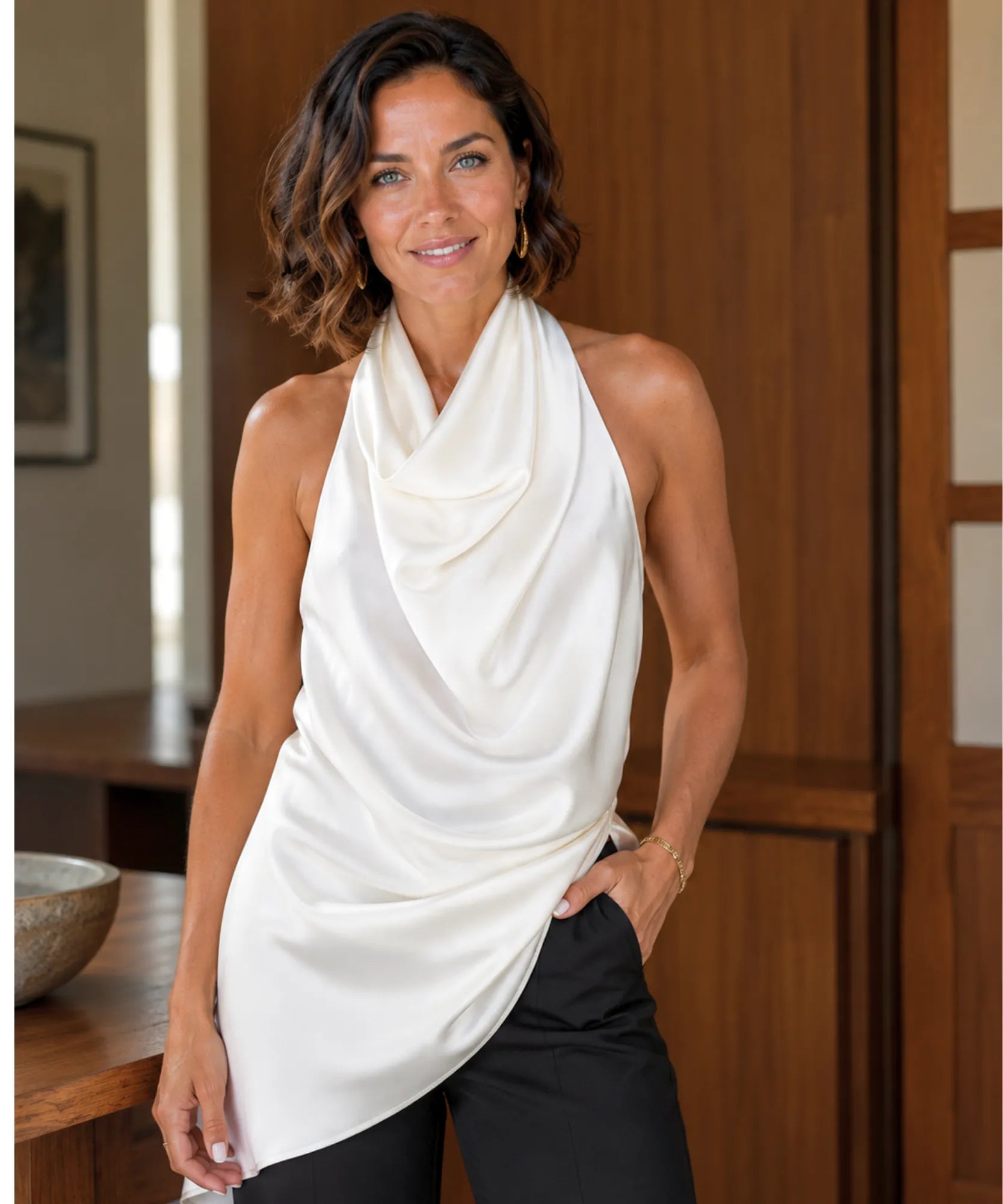 Ivory sleeveless satin halter top styled with black trousers