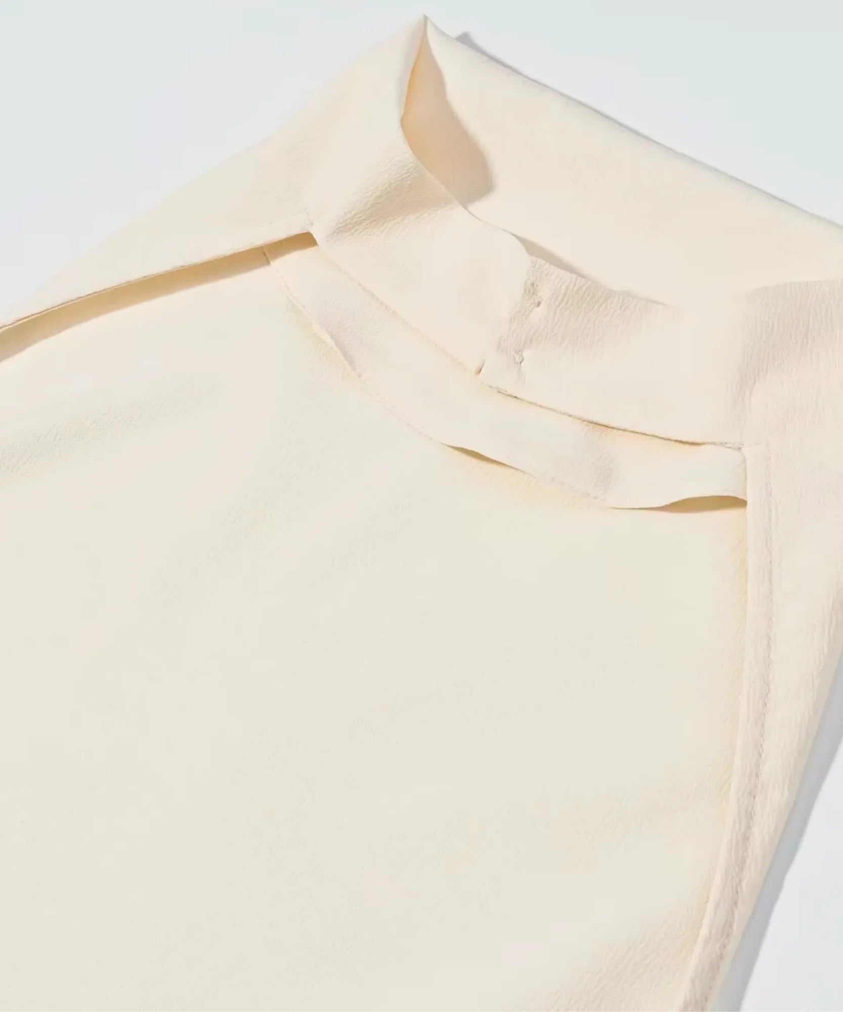 Cowl neck detail on an ivory satin halter top