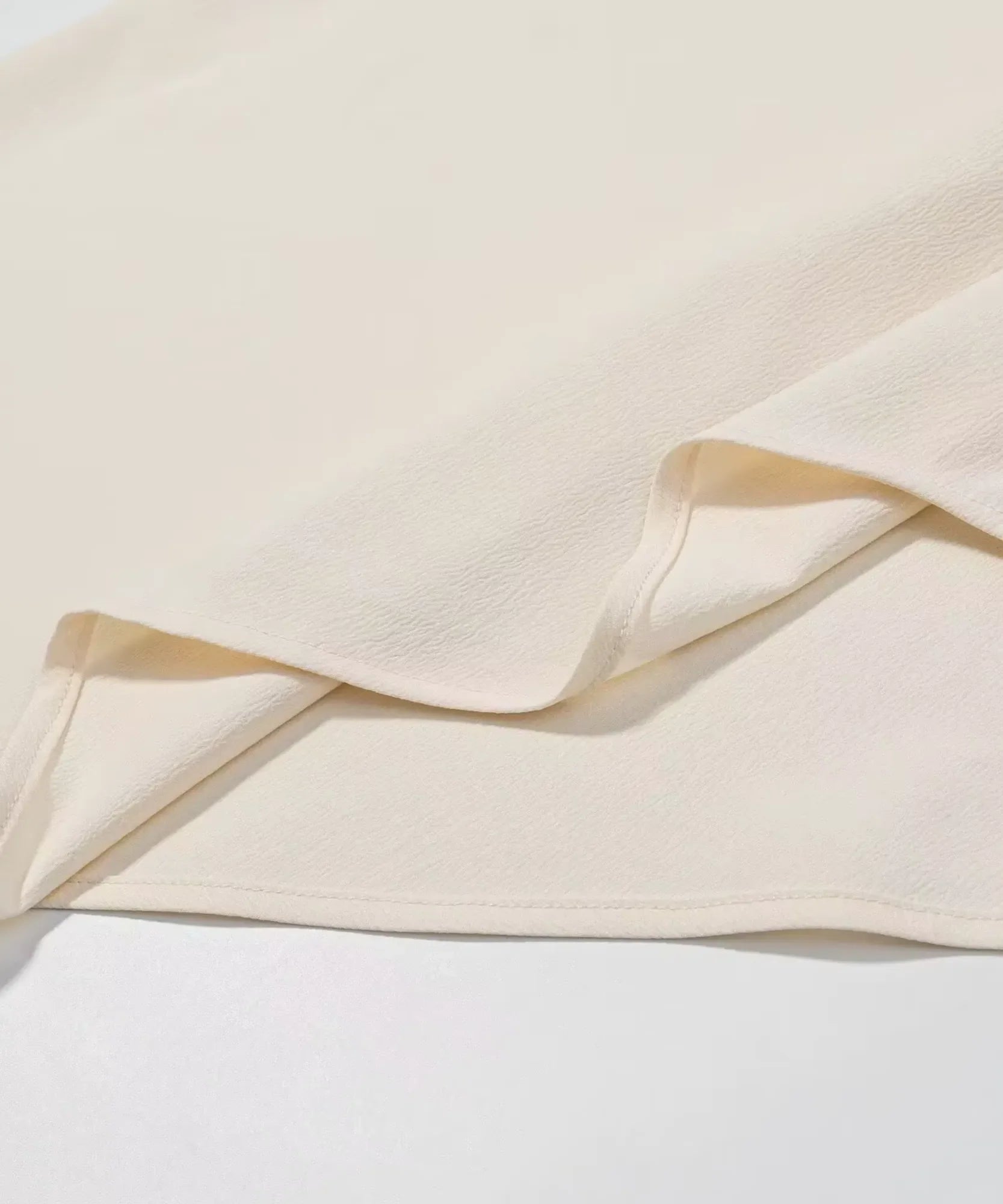 Hem detail on an ivory satin halter top