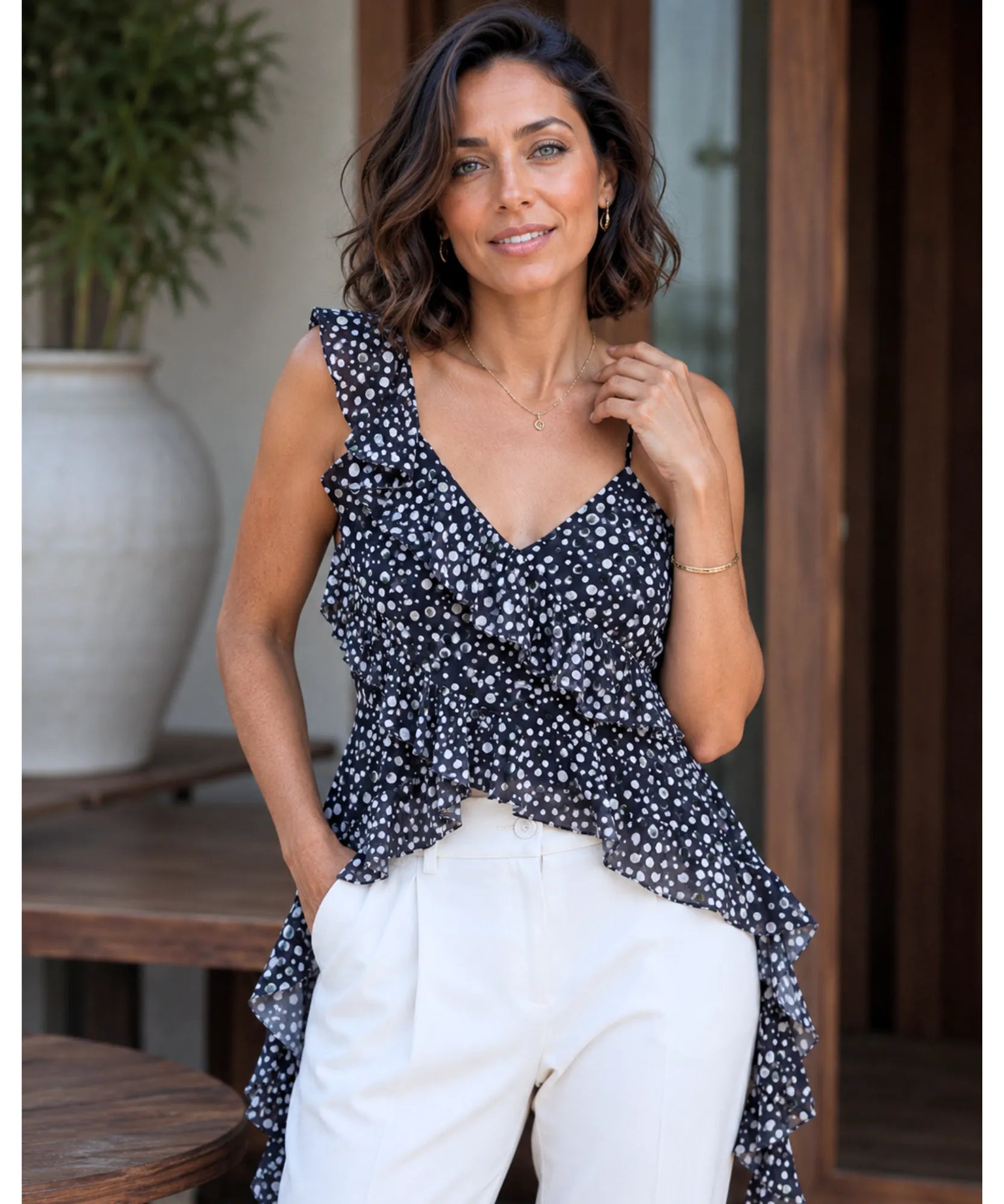 Black floral ruffle top with asymmetrical hem styled with white trousers