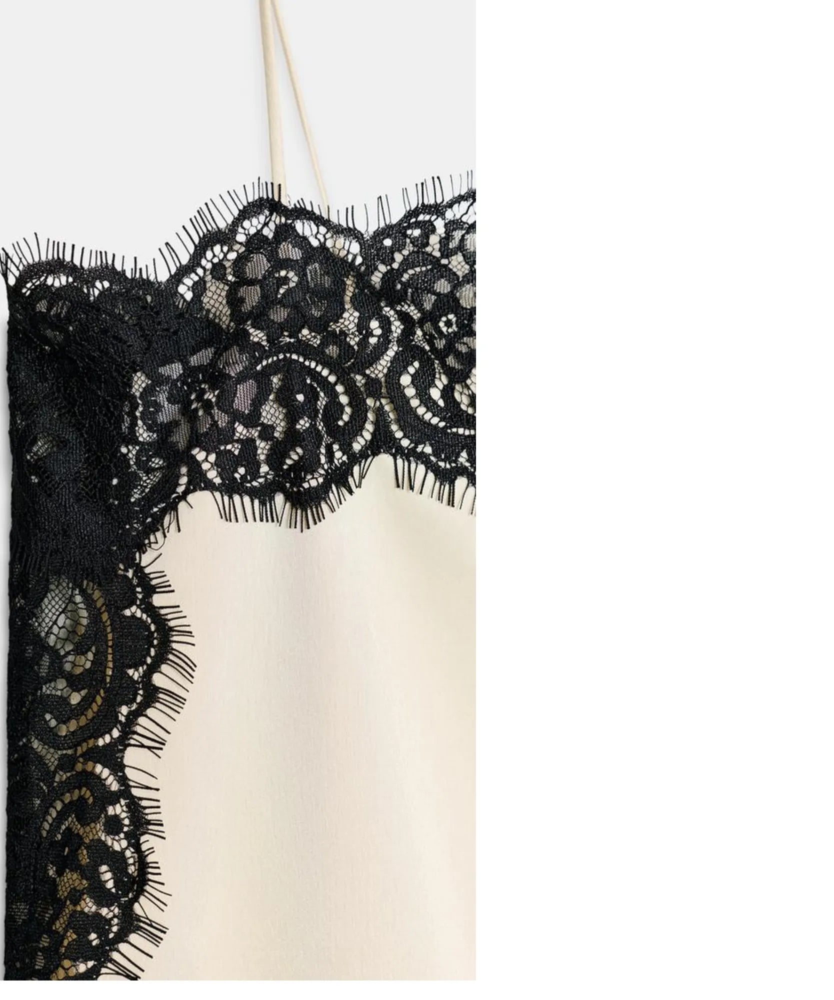 Close-up of black lace trim on ivory satin cami top