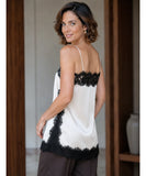 Back view of ivory satin cami top with black lace trim and dark trousers
