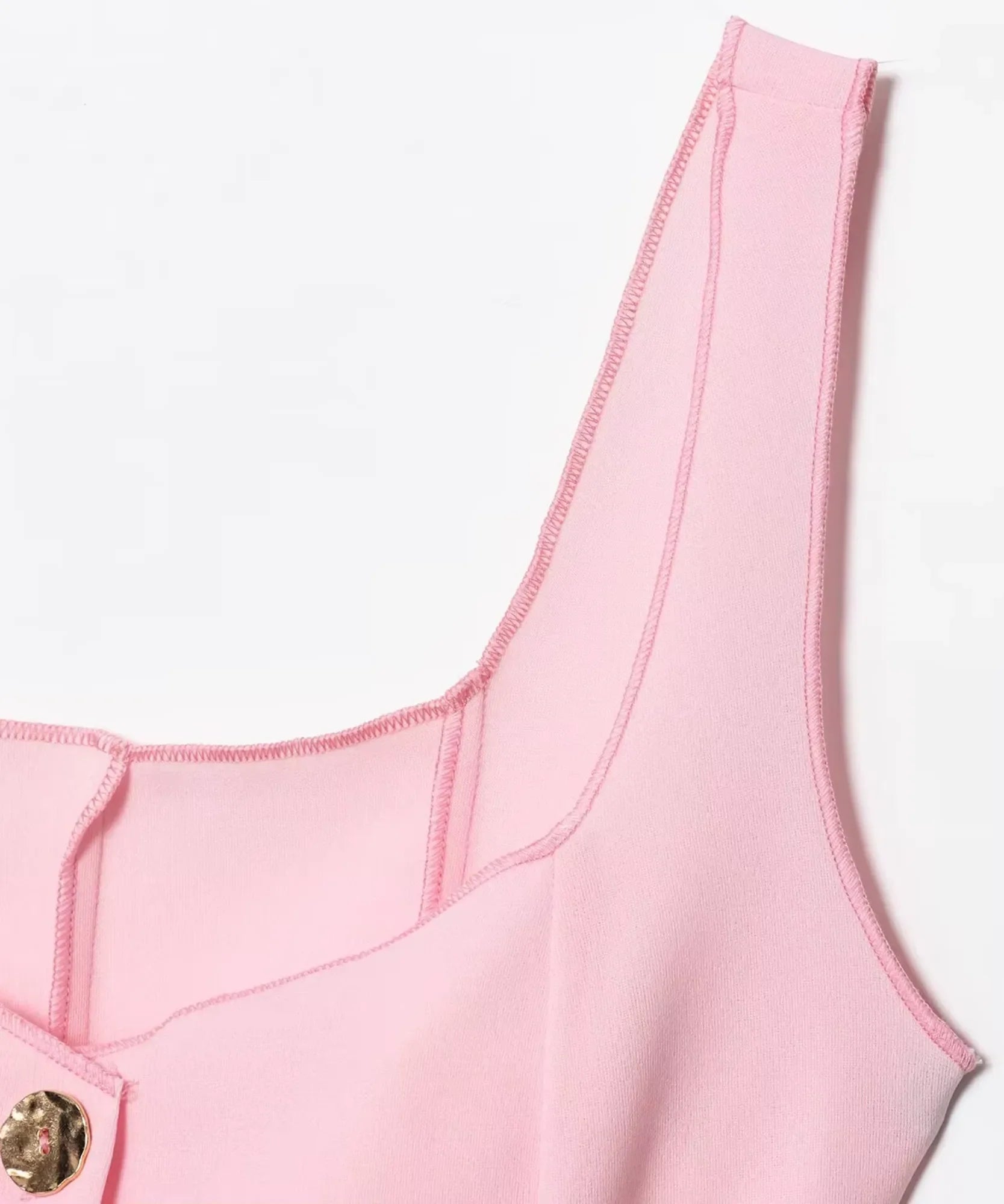 Detail of the wide strap and seam finish on a light pink peplum tank top