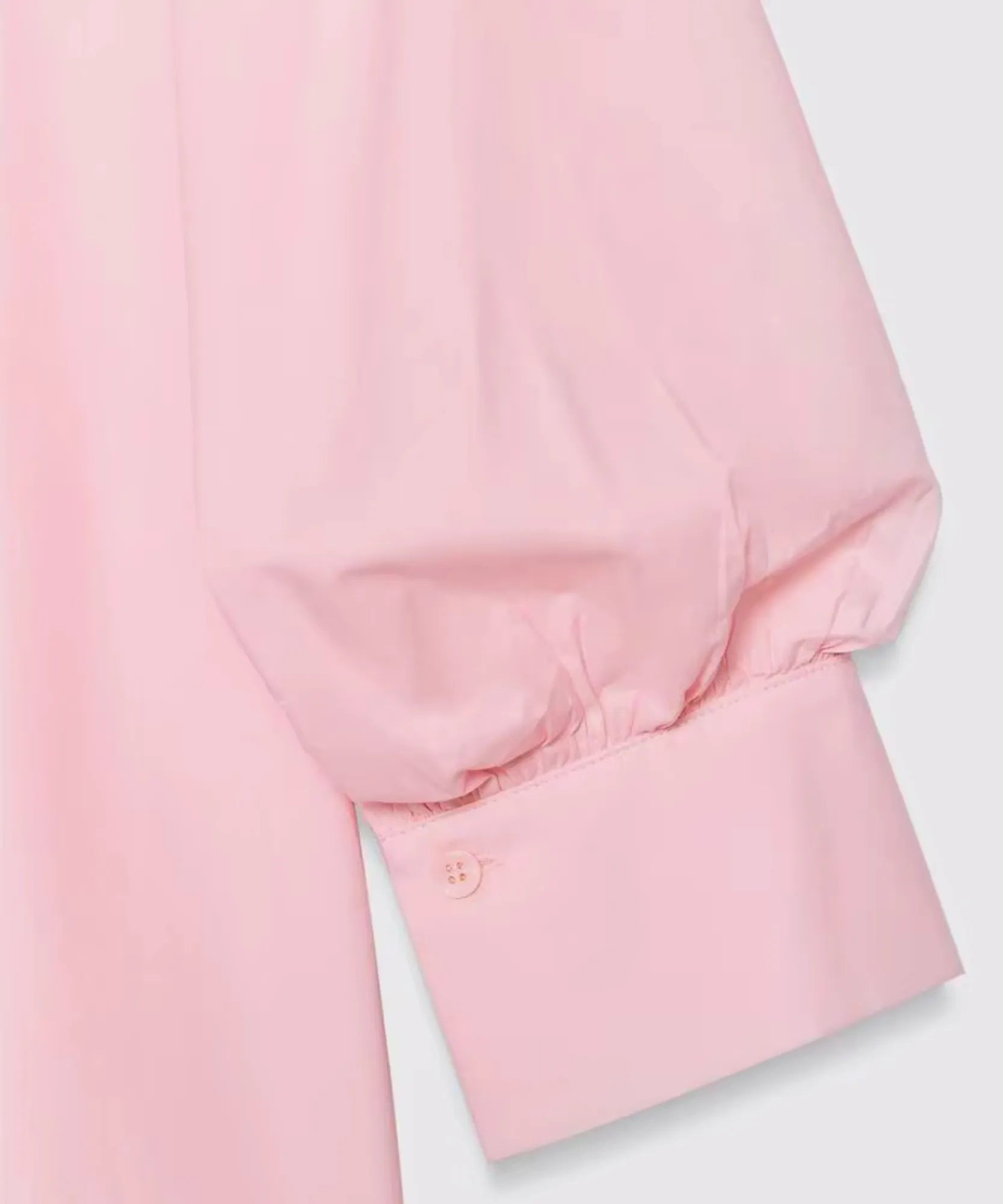 Close-up of gathered puff sleeve cuff on light pink blouse