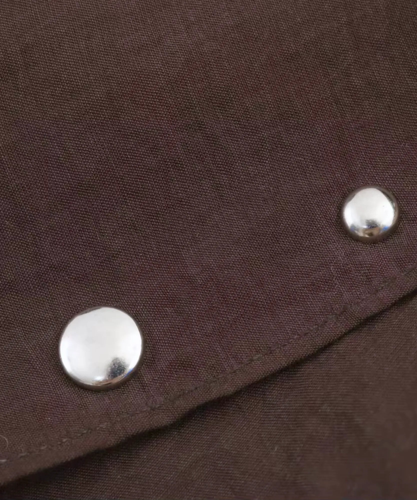 Close-up of silver metal studs on dark brown sheer fabric