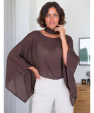 Dark brown sheer cape top with open sides and studded hem, hand on hip