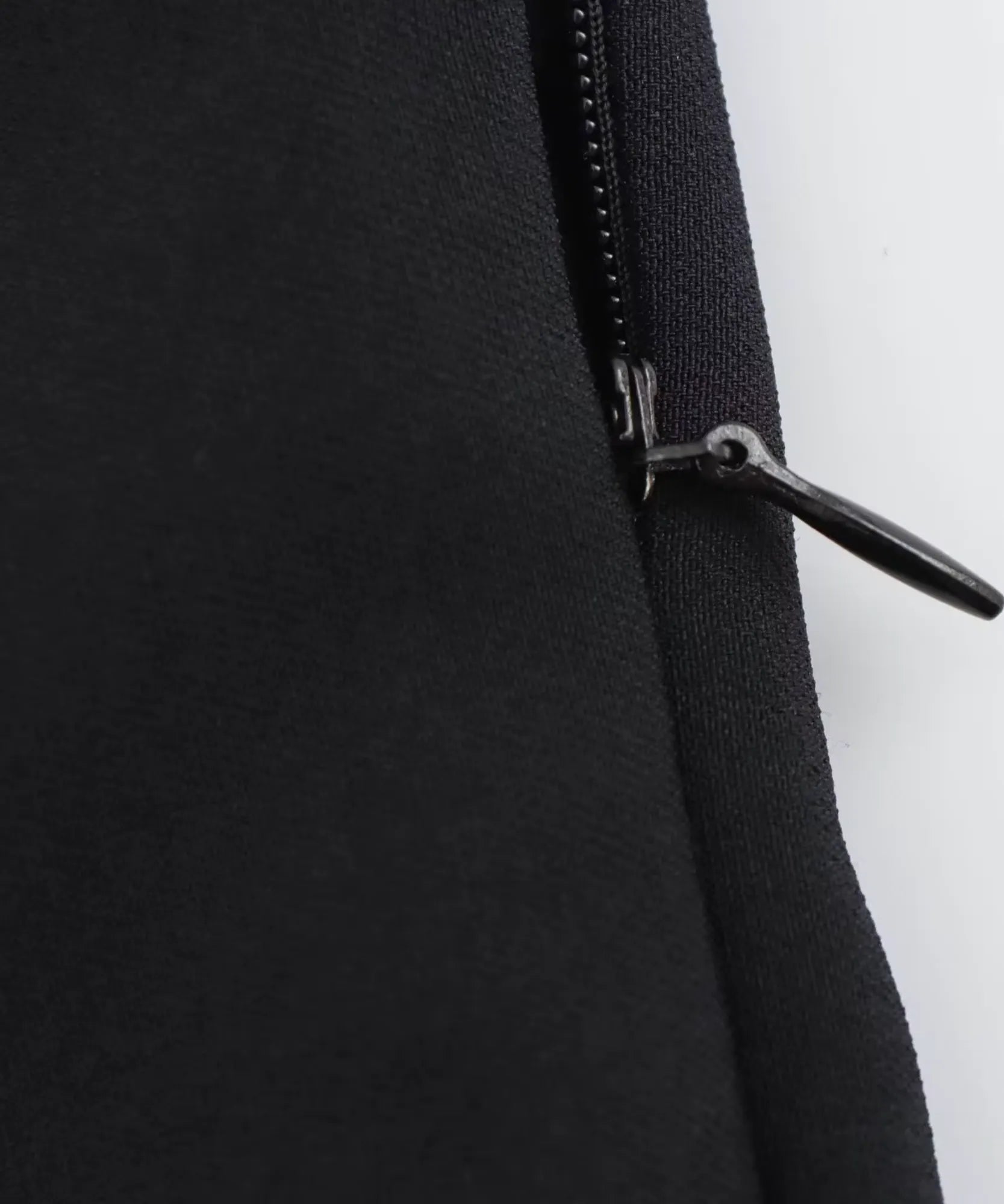 Invisible side zip detail on a black peplum tank top