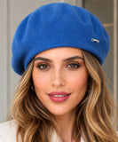 Woman wearing a cobalt blue wool-blend French beret with a metal brooch
