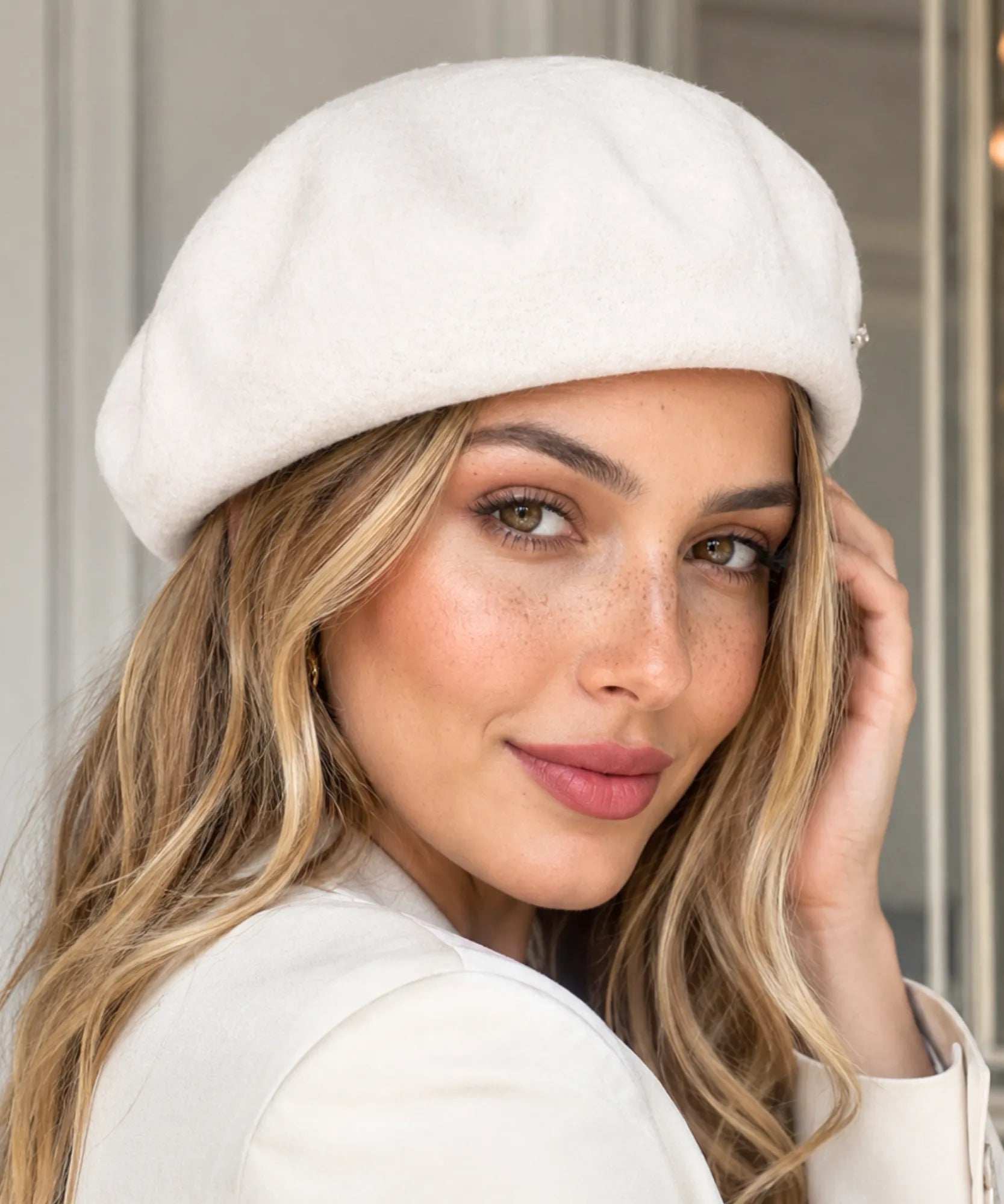 Woman wearing an ivory wool-blend French beret with a metal brooch