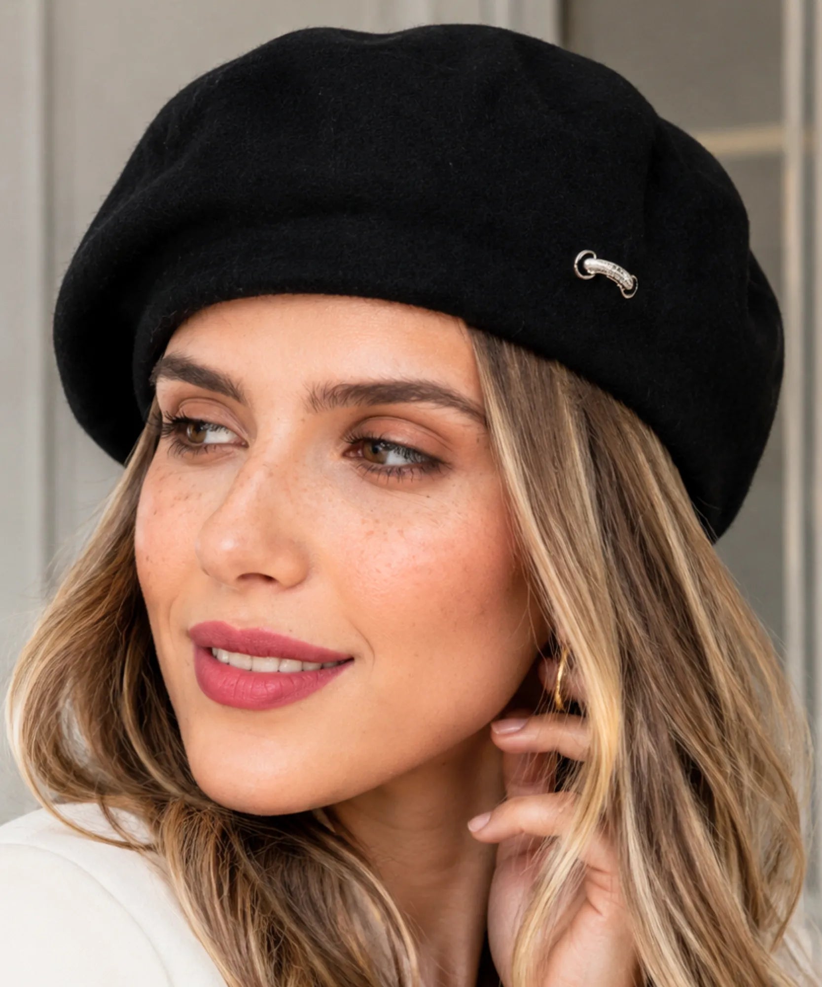 Woman wearing a black wool-blend French beret with a metal brooch