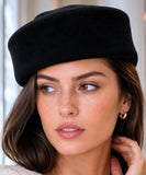 Woman wearing a black wool pillbox hat with a satin lining