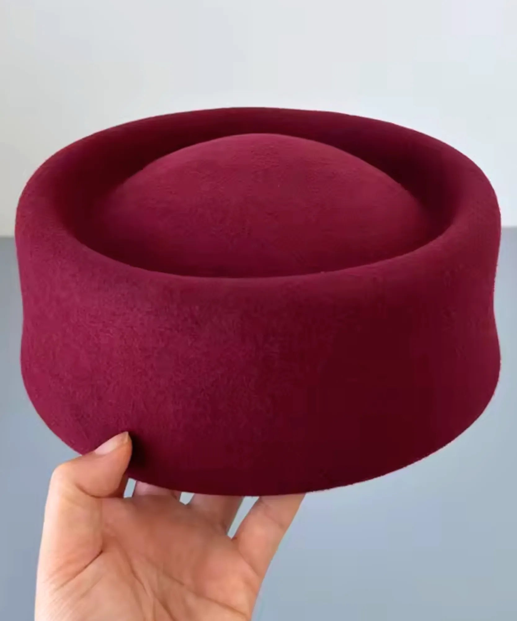 Burgundy wool pillbox hat shown from above, highlighting its cylindrical shape