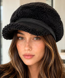 Woman wearing a black plush sherpa newsboy cap with a suede brim