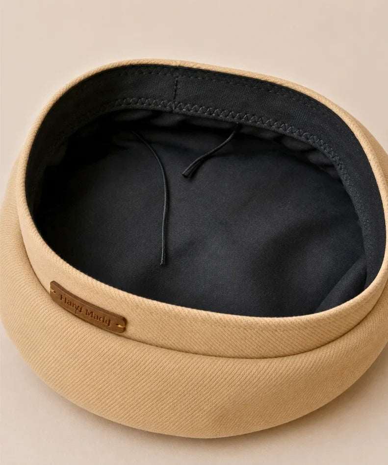Interior view of a camel structured twill French beret with its black lining and hand-made tag