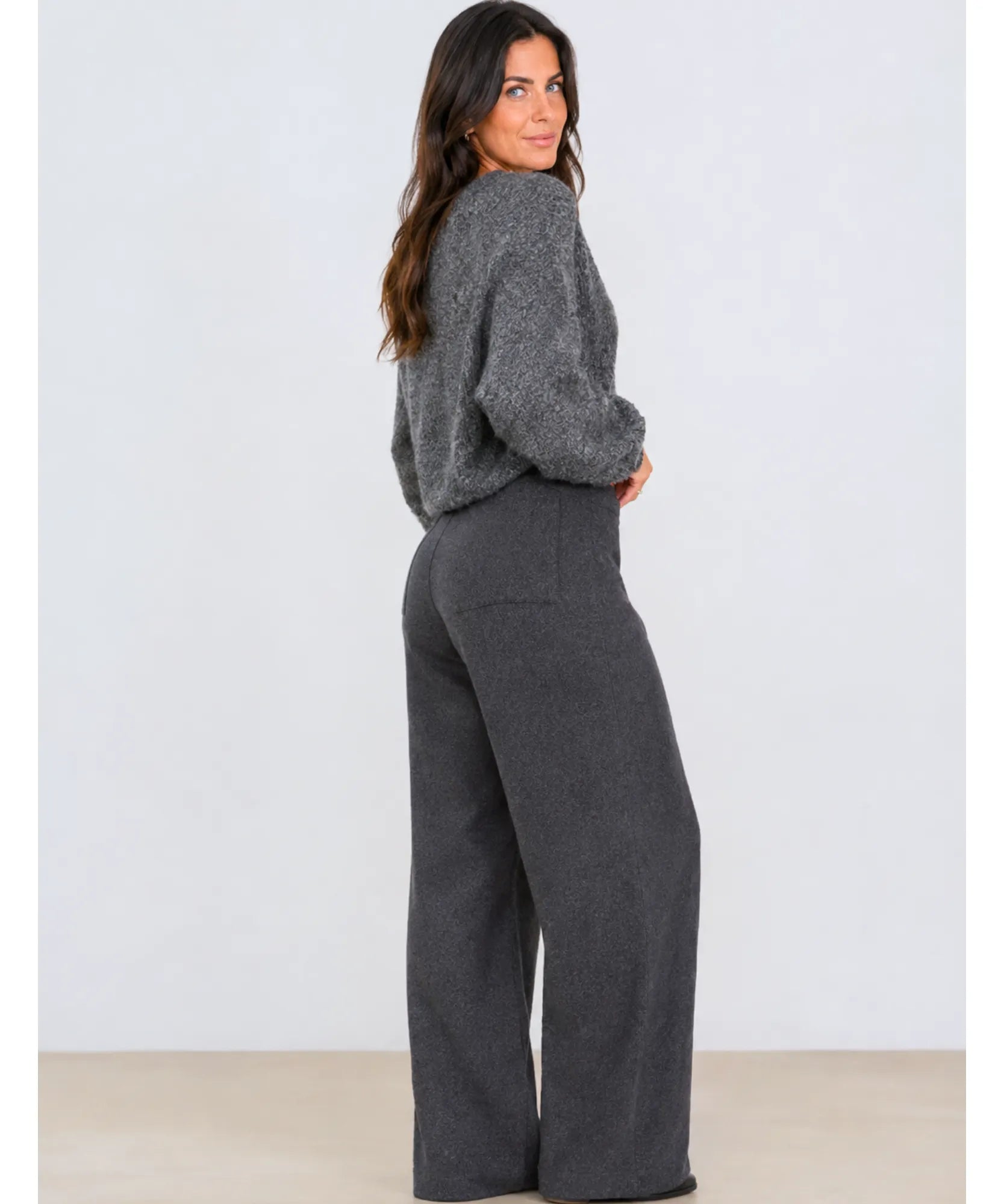 Side view of charcoal wide leg wool blend trousers with a grey knit sweater