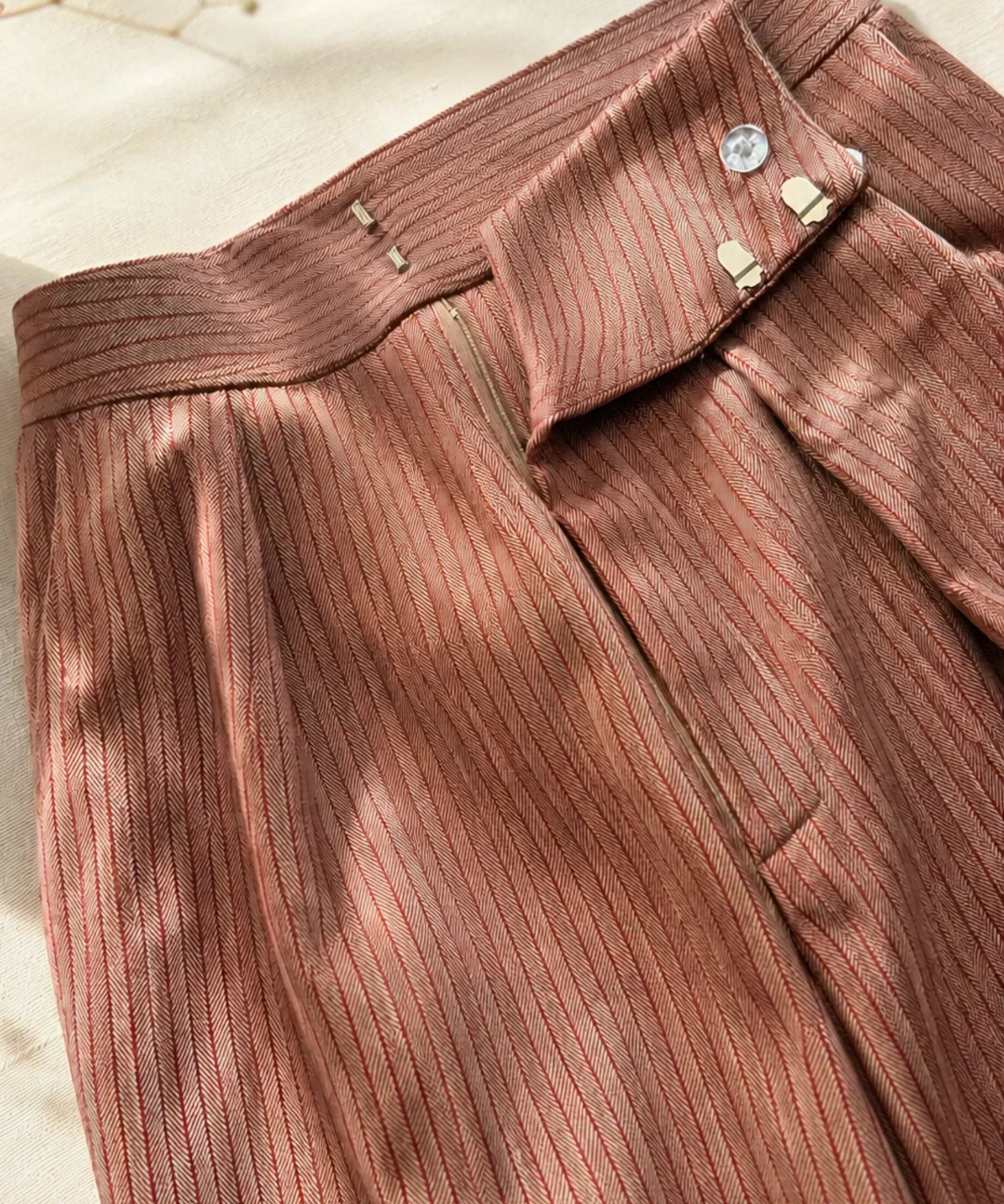 Close up of the pinstripe fabric and hook closure on mocha barrel pants