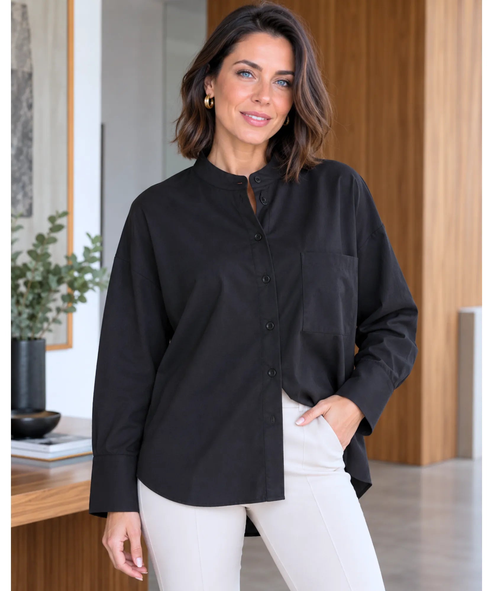 Women's relaxed black button up shirt with a rounded hem and ivory trousers