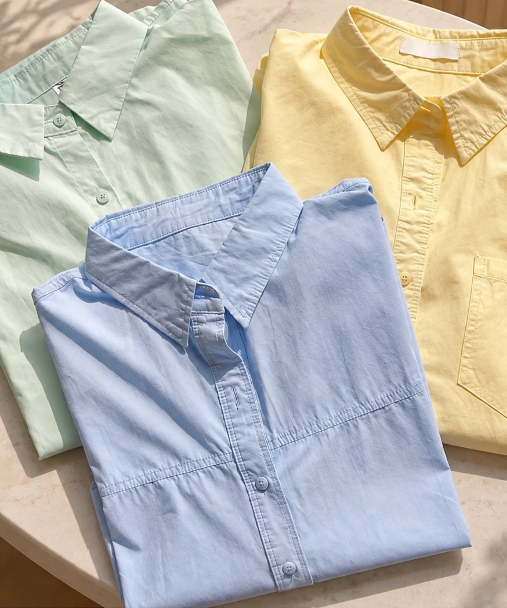Women's long sleeve shirts folded in light green, light yellow and light blue