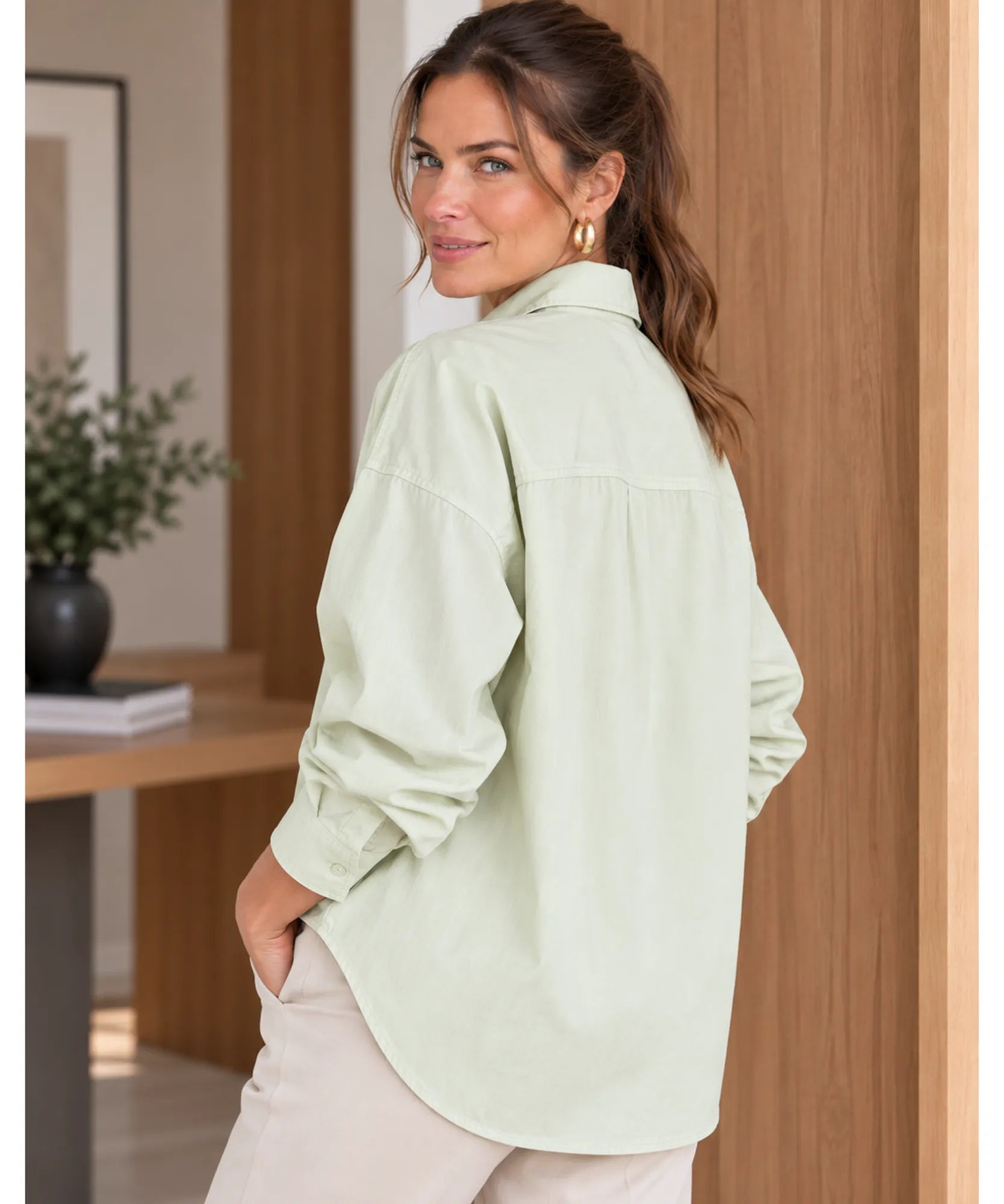 Women's long sleeve shirt in light green, back view with rounded hem