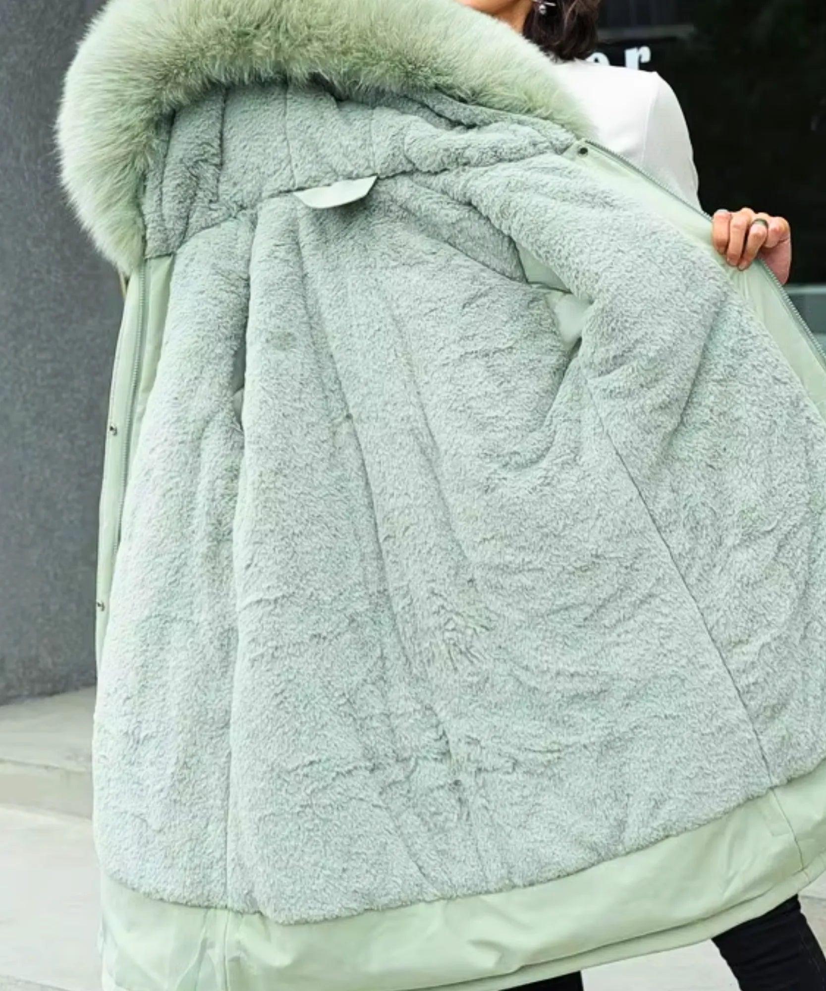 Woman wearing the sage green parka coat with hood up