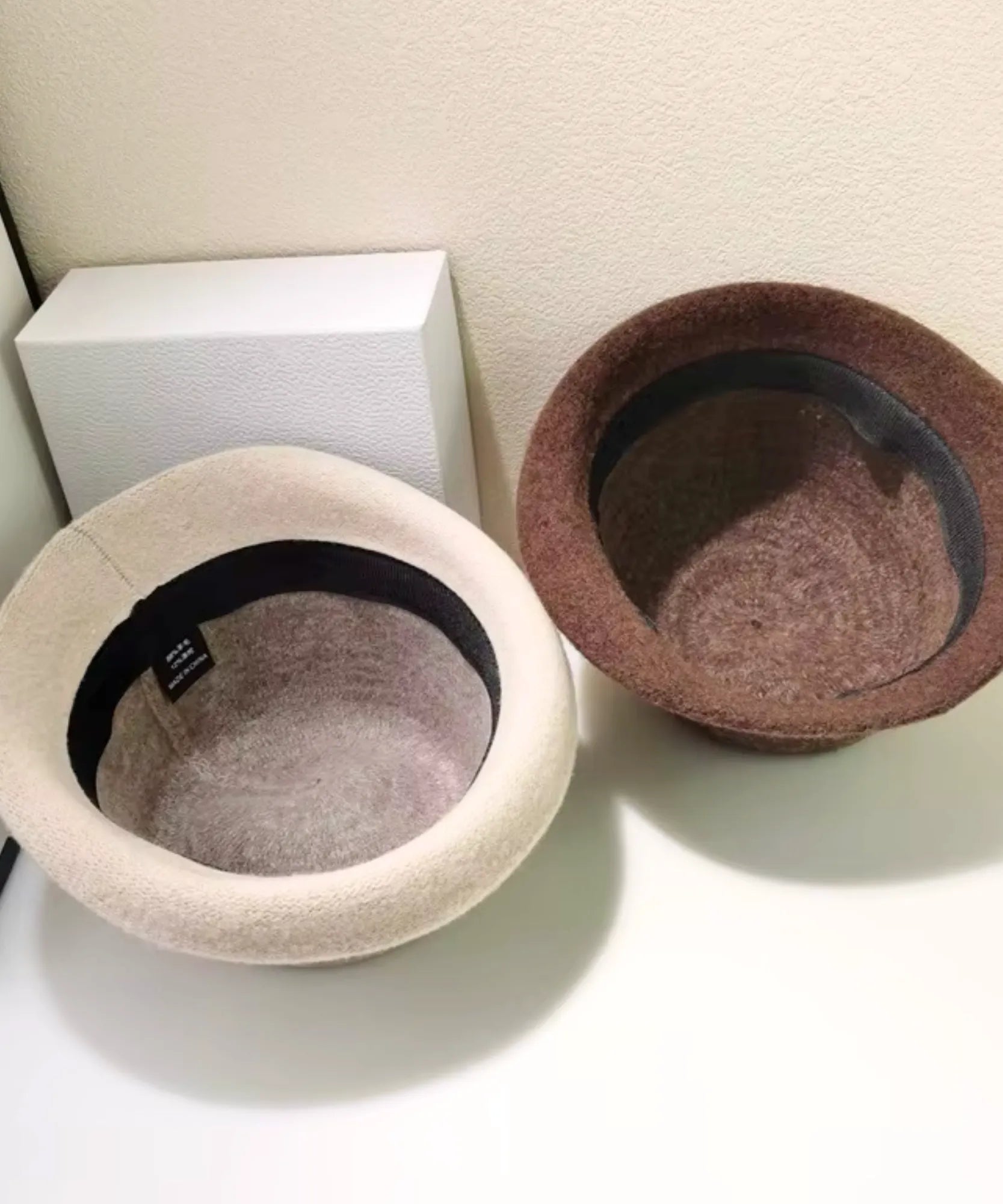 Two Women's Wool Felt Cloche Hats in Oatmeal and Mocha shown from above, highlighting the soft interior lining