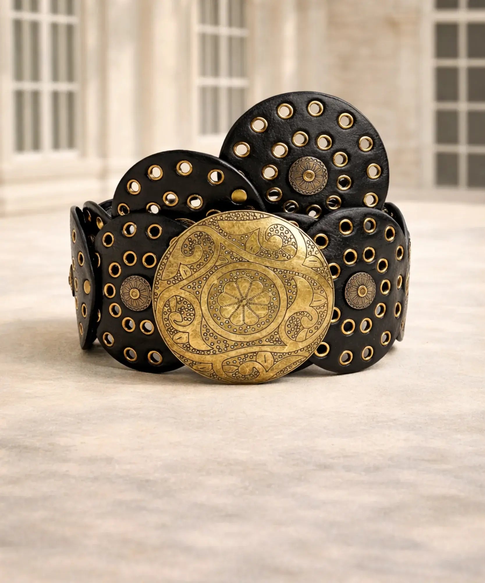 Women's black concho belt with gold buckle worn over a dress