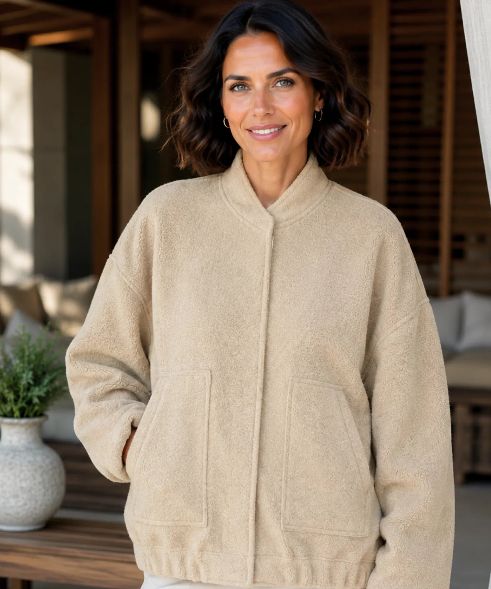 Woman wearing an oversized boucle bomber jacket in nude