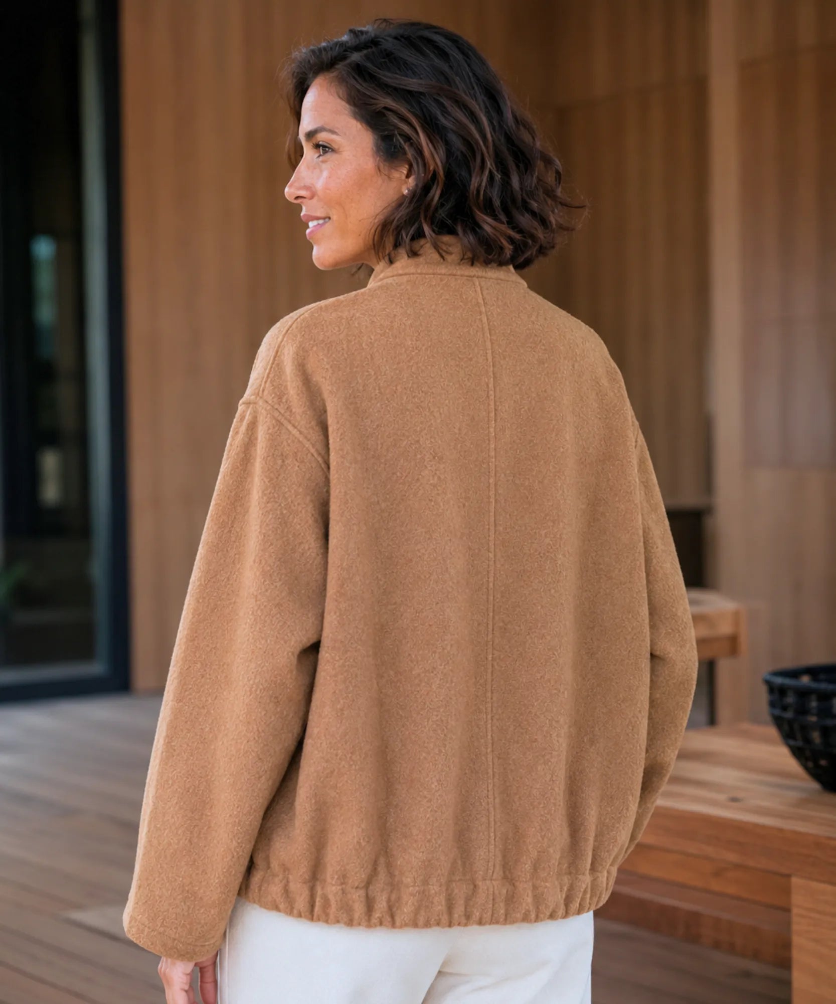 Woman wearing an oversized boucle bomber jacket in camel
