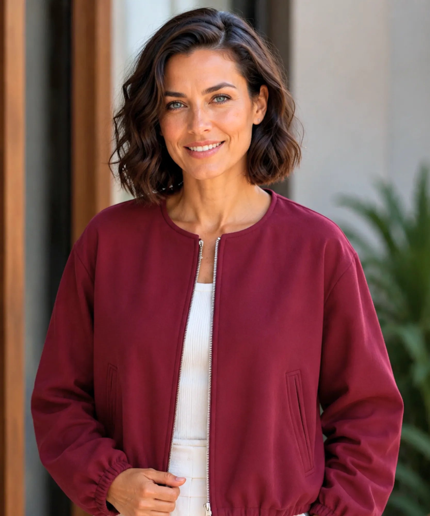 Woman wearing a cropped wool bomber jacket in burgundy
