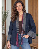 Women's denim kimono jacket worn over a tee with light wash jeans and a scarf