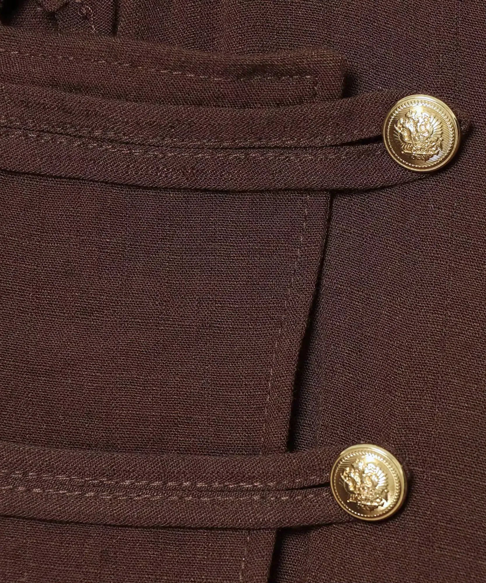 Close up of gold buttons on women's brown jumpsuit