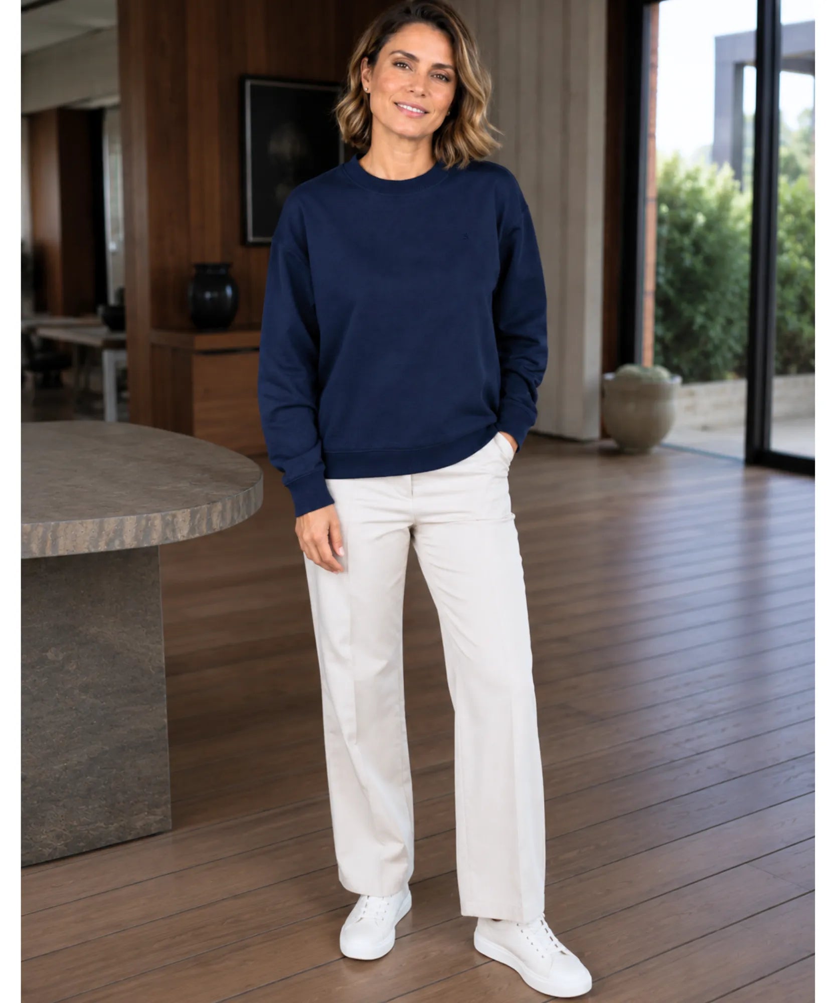 Women's navy crew neck sweatshirt styled with white wide-leg pants and sneakers