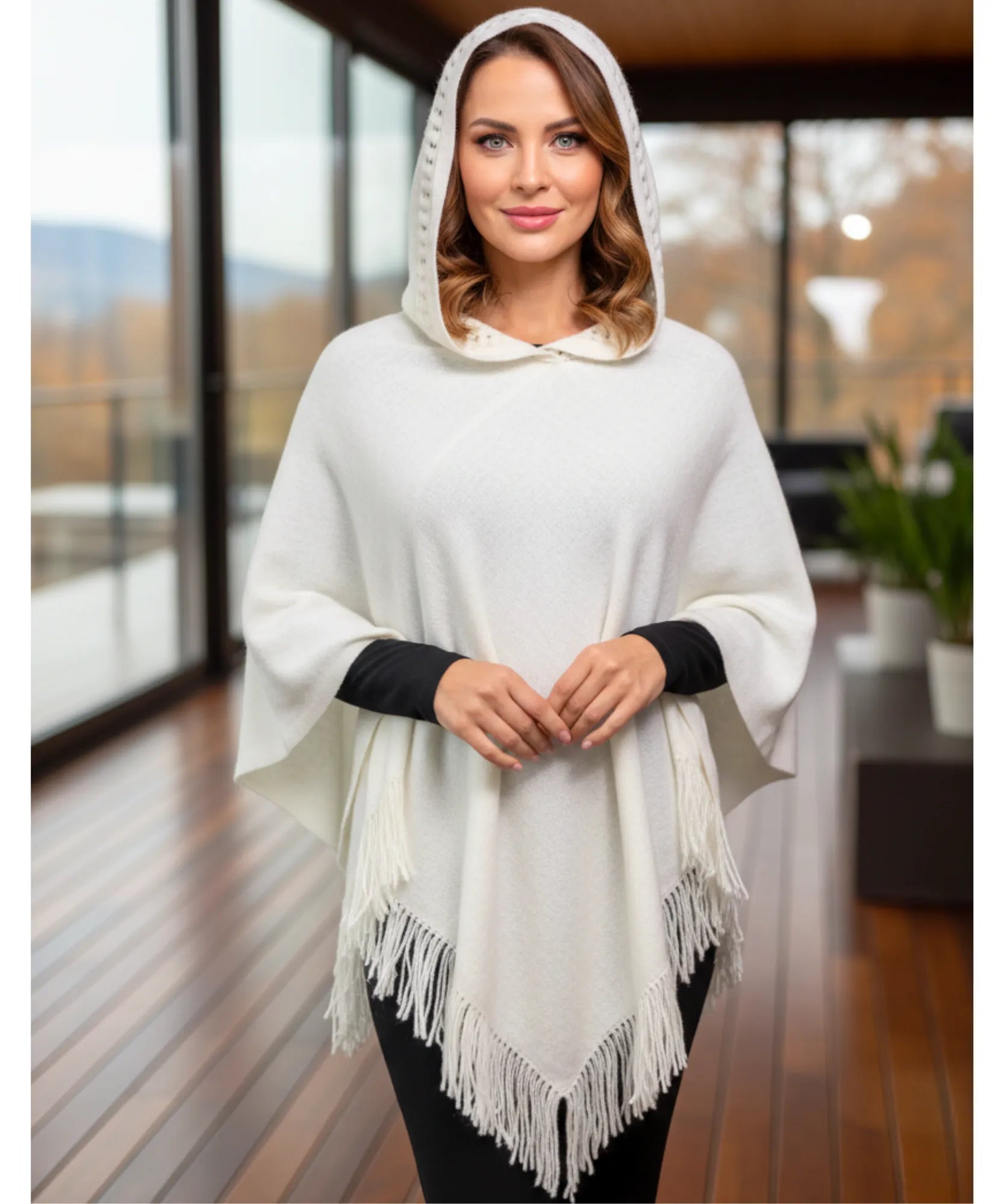Women's hooded poncho sweater in white chunky knit with fringe trim, hood up