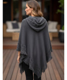 Women's hooded poncho sweater in grey chunky knit, back view showing hood and fringe hem