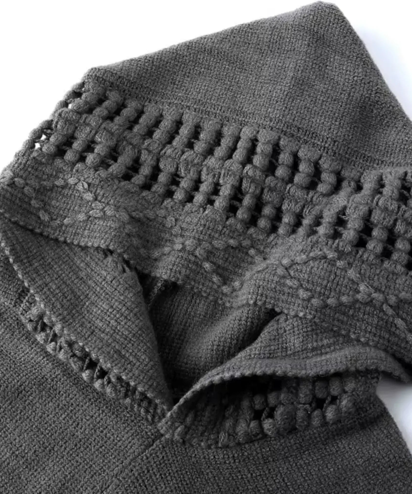 Women's hooded poncho sweater in grey chunky knit, styled indoors