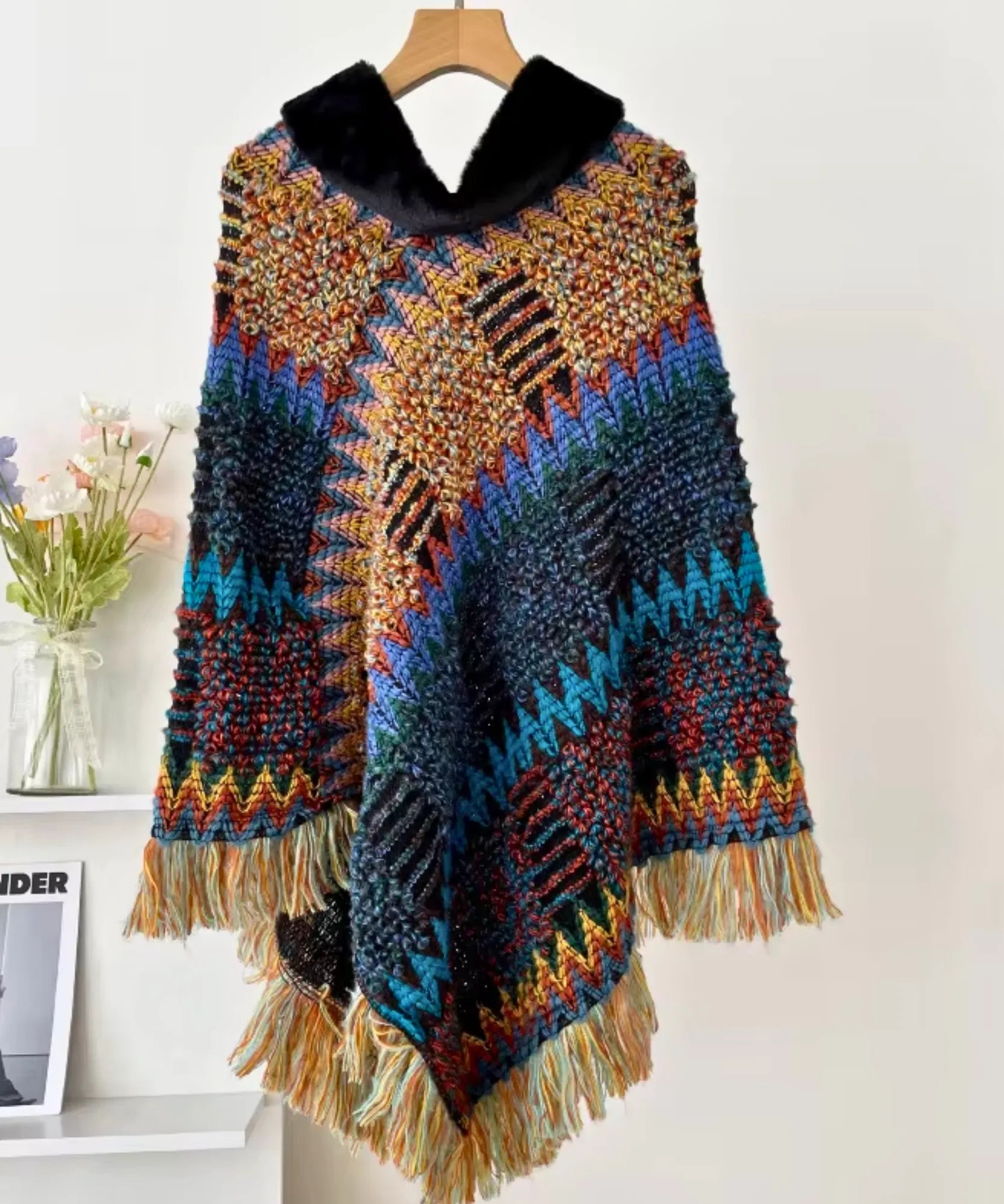 Women's boho poncho sweater in rainbow multicolor chunky knit with fur-trim collar, hanging detail view