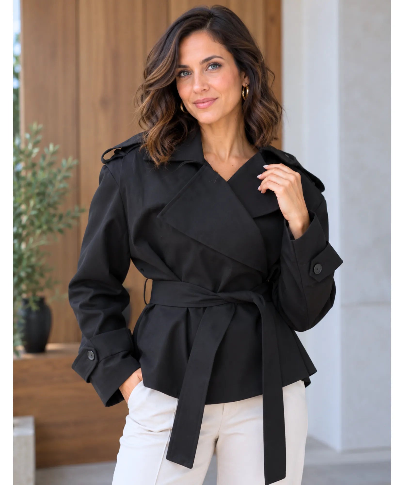 Women's short trench coat in black worn with the collar open
